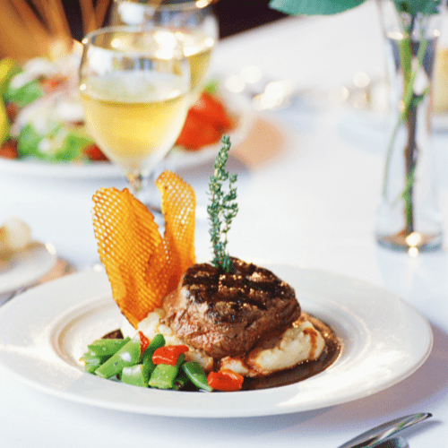A fancy steak atop mashed potatoes with greens